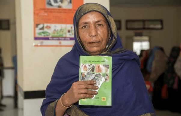 A patient holding her hypertension treatment card at an enrolled facility