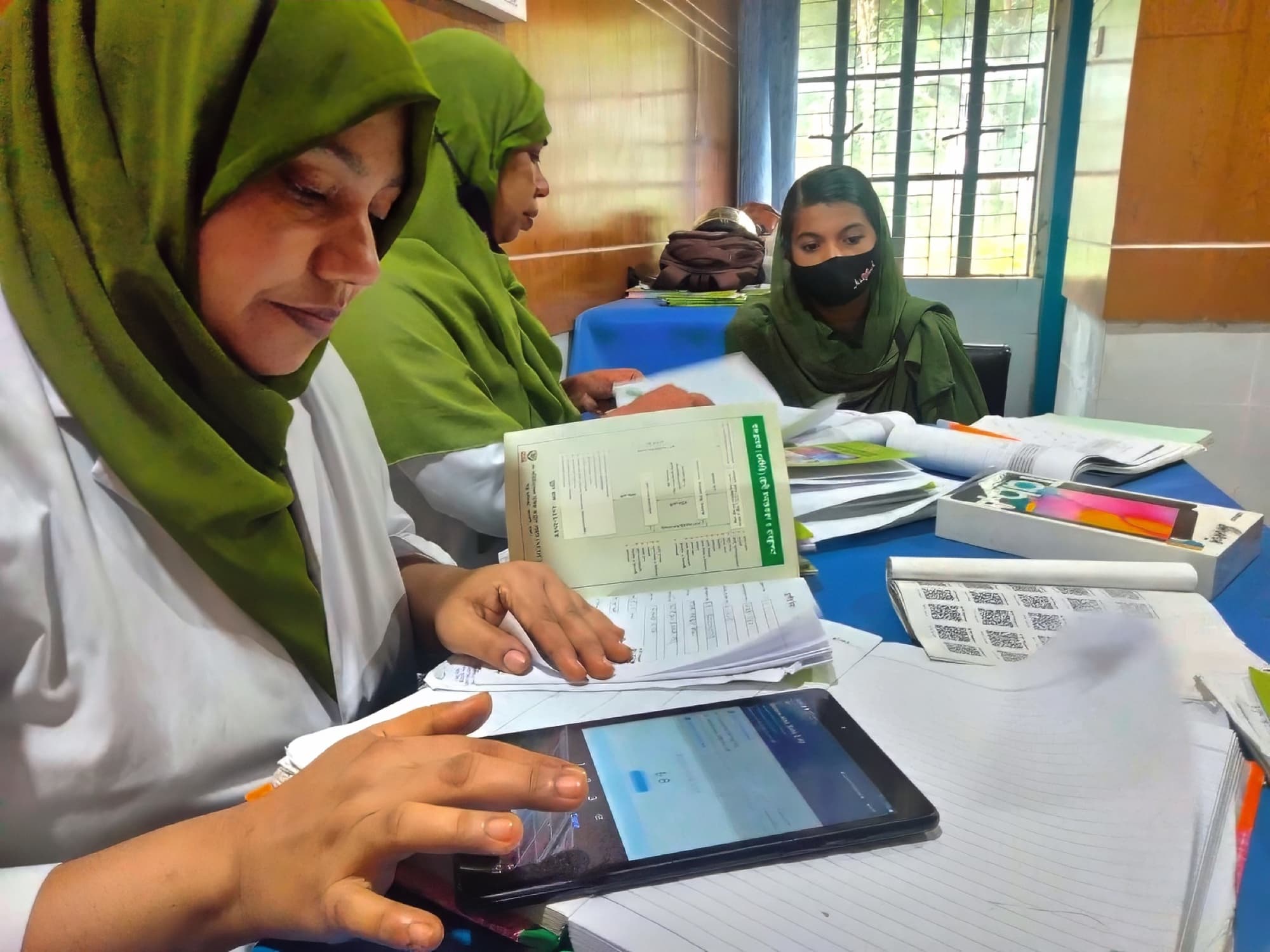 Two health workers recording a patient's blood pressure in the Simple app on a tablet