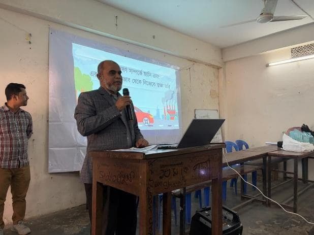 A facilitator presenting on air pollution to students in a school hall