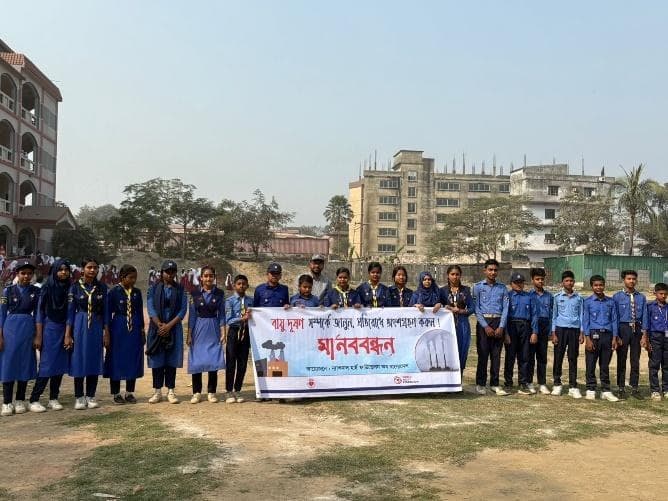 Scouts and girl guides lined up behind the campaign banner outside a school